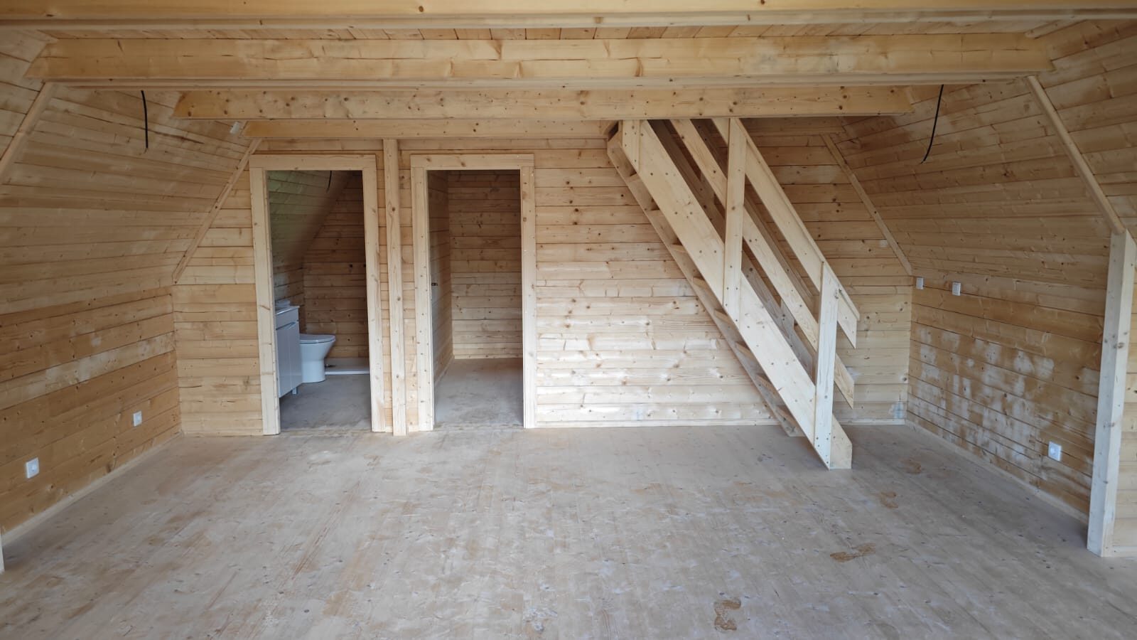 Interior da A-Frame: sala em madeira maciça com escada para o mezanino, casa de banho e arrumos